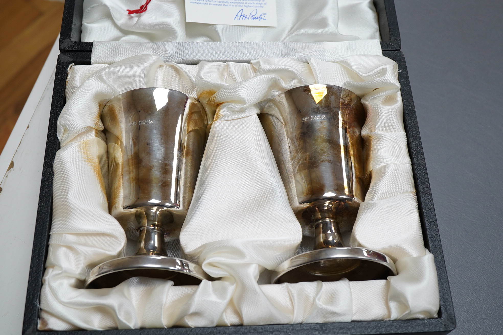 A cased pair of silver pedestal goblets, by Parkinson Silversmiths Ltd, Sheffield, 1984, height 10.6cm, 5.5oz, the case with engraved presentation plaque.